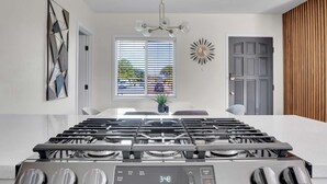 Une cuisine moderne dotée d’une hotte en acier inoxydable, d’une cuisinière à commandes numériques et d’une fenêtre avec stores.
