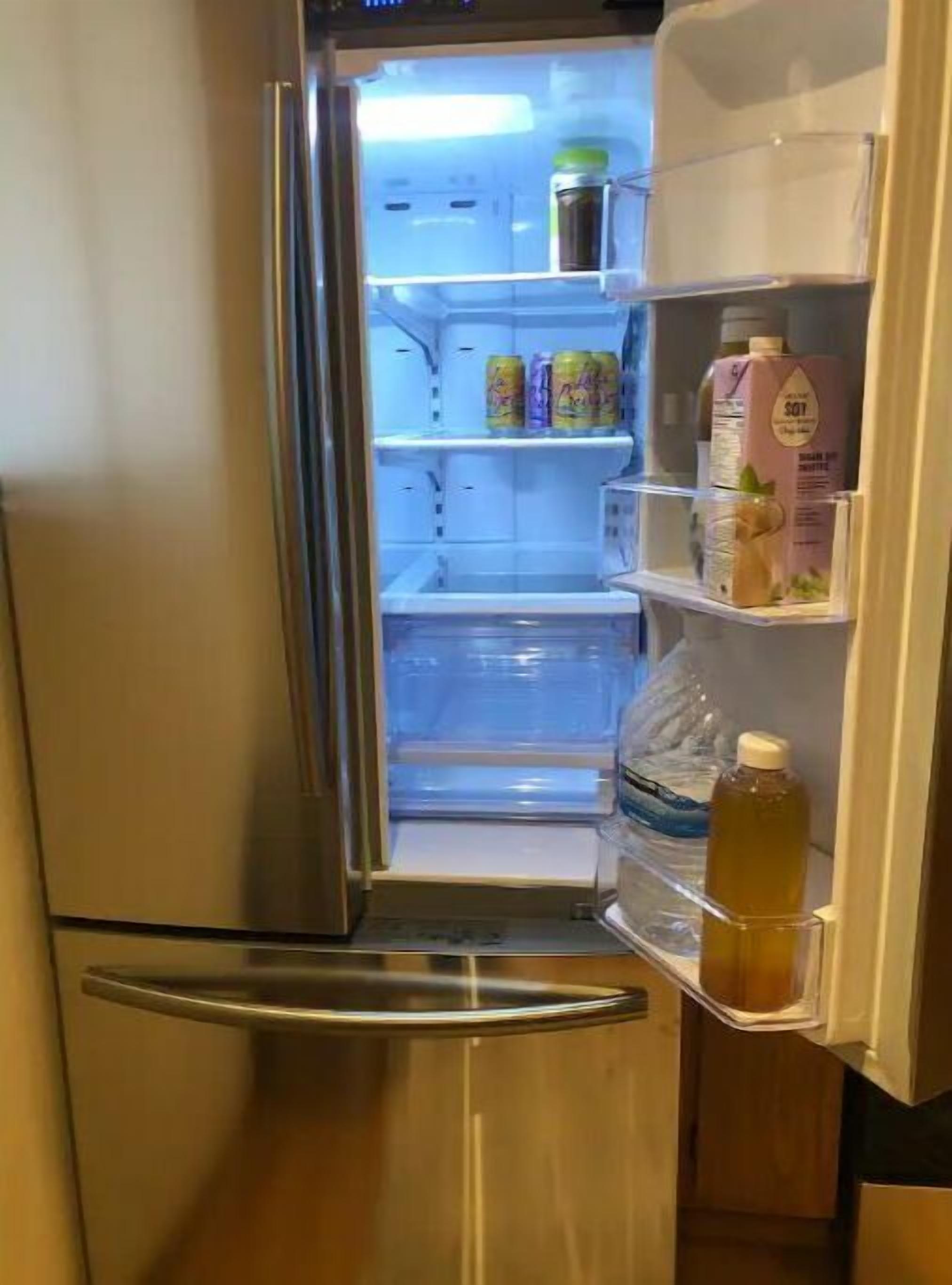 Ein Edelstahl-Kühlschrank mit Regalen, auf denen Getränke und eine Milchkarton stehen.