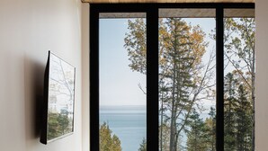 Une chambre avec une grande fenêtre, un plancher en bois et un lit.