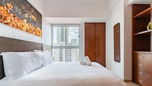 A modern hotel room with a large bed, a wooden wardrobe, and a city view through the window. - Anahuac Apartments by VH (Mexico City)