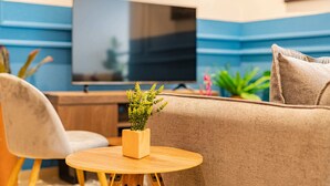 A modern living room with a sofa, a round wooden table, and a television. - Anahuac Apartments by VH (Mexico City)