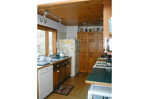 Enjoy cooking in this well-equipped kitchen with a dishwasher, refrigerator, and window offering a view of the outdoors.