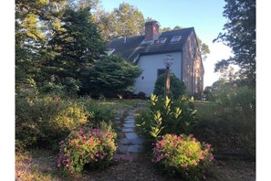 Traditional house with a gabled roof and chimney, set amidst a beautifully maintained garden.