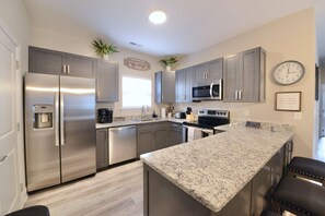A modern kitchen with stainless steel appliances, granite countertops, and grey cabinetry.