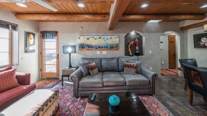 A living room with a leather sofa, a coffee table, and a painting on the wall. - El Corazon - Walking Distance to the Plaza (Santa Fe)