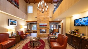 A spacious lobby with leather sofas, a fireplace, a large TV, and a chandelier. - El Corazon - Walking Distance to the Plaza (Santa Fe)