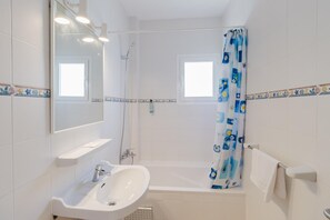 Un bagno con lavandino, specchio, doccia e finestra.