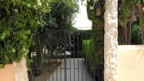 Una entrada protegida por un muro de piedra y una reja de metal.