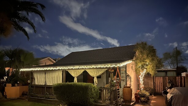 Una casa con portico coperto, luci decorative e un prato curato.