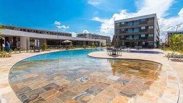 Una piscina con un diseño de mosaicos único, rodeada por un edificio moderno con varios pisos y balcones.