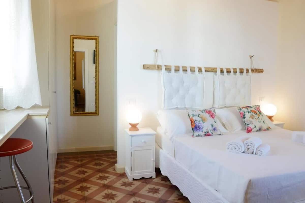 A bedroom with a bed, bedside tables, a mirror, and a patterned floor.