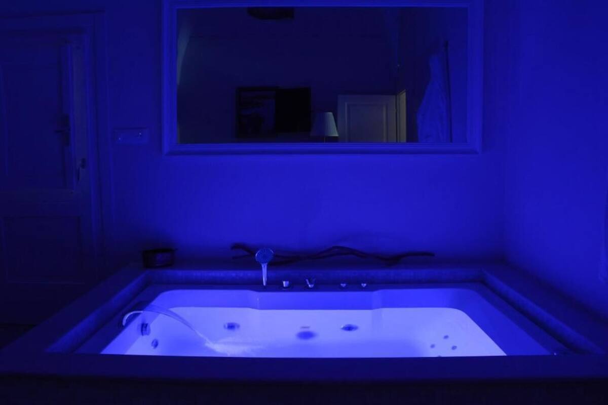 A bathroom with a bathtub, a mirror above it, and a door to the left.