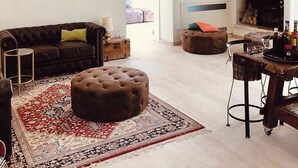 Un salón espacioso con un techo alto en arco, una araña, una chimenea y un cuadro grande en la pared.