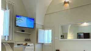 Un baño moderno con un espejo grande, una bañera y un televisor montado en la pared.