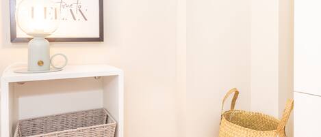 A framed artwork with the text "time to" on a wall, a white shelf with a wicker basket, and a woven basket on the floor.