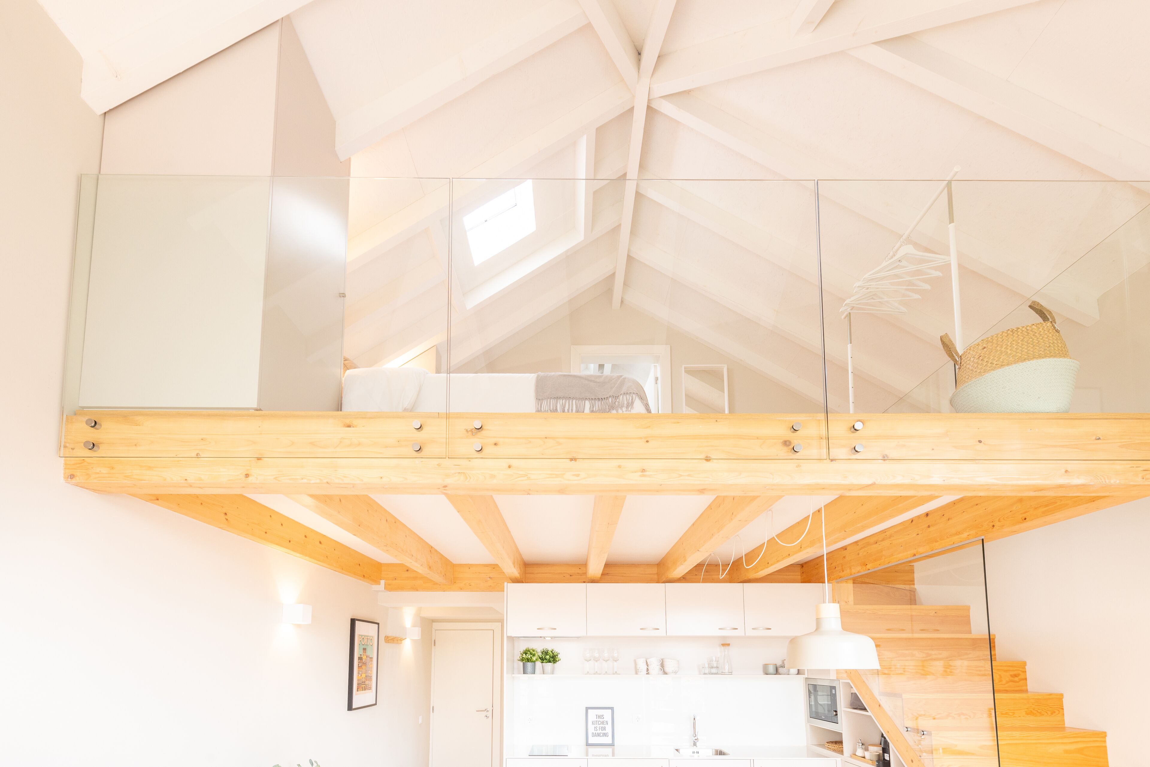 Quarto estilo loft moderno, com teto de vidro, vigas de madeira, área de cozinha inferior e escada.
