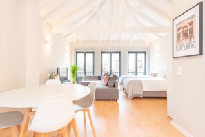 A modern, well-lit room with a dining area, a sofa, a bed, and large windows. - 12 Sweet Caroline (Porto)