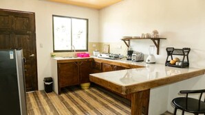 Una cocina compacta con encimera de madera, un fregadero, un refrigerador y una ventana.