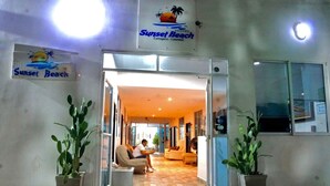 A hotel entrance with a sign reading "Sunset Beach" and a person sitting on a bench inside. - HOTEL SUNSET BEACH (Cartagena)