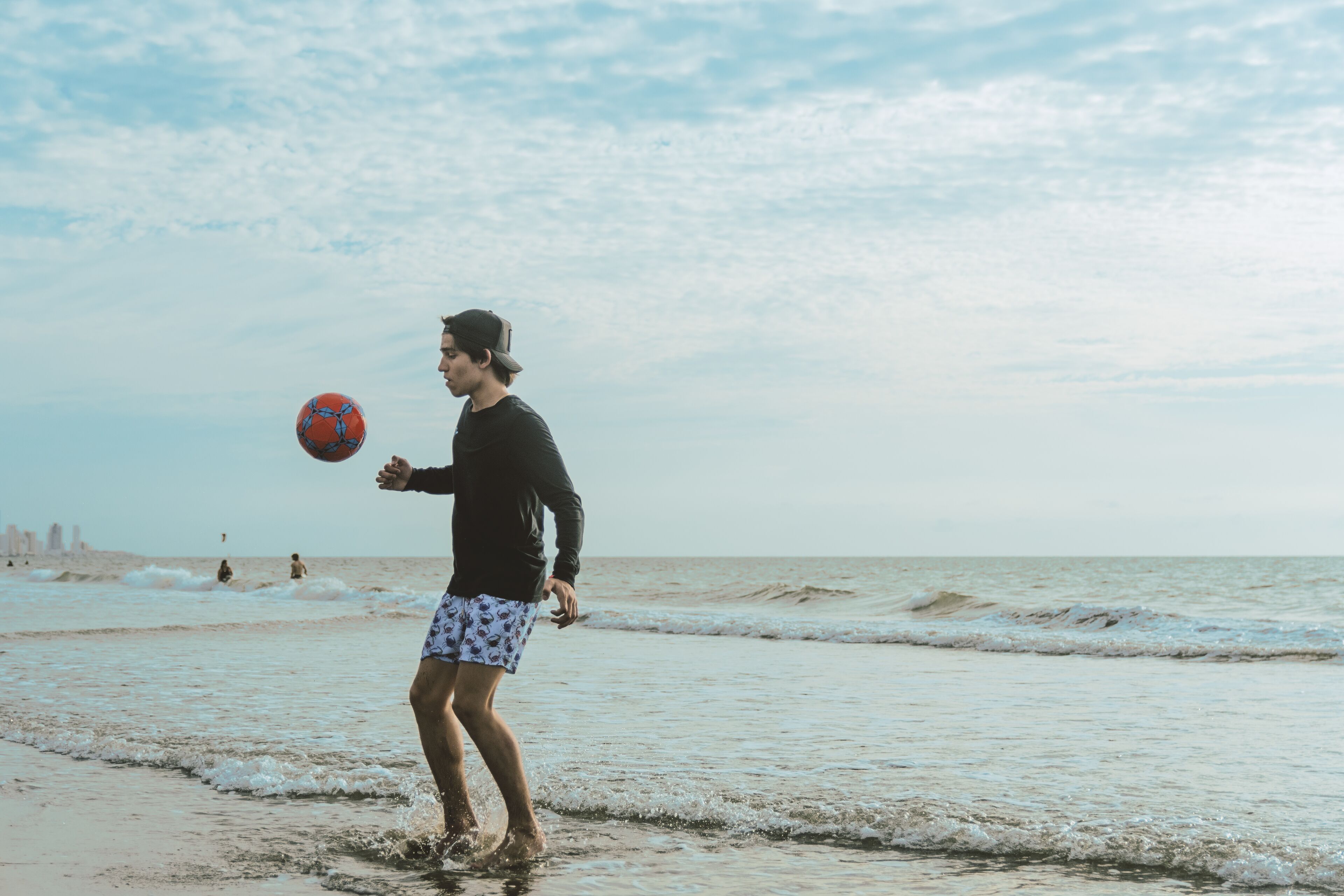 A person playing with a ball on a beach.