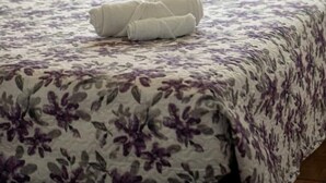 Ein Bett mit floralem Überwurf und einem aufgerollten weißen Handtuch.
