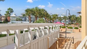 A resort with a white fence, palm trees, and a pool area with umbrellas. - First Floor Condo • Walk to Beach • Sleeps 4 (Mexico Beach)