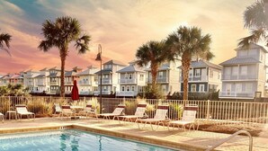 A swimming pool with lounge chairs and a row of beachfront bungalows. - First Floor Condo • Walk to Beach • Sleeps 4 (Mexico Beach)