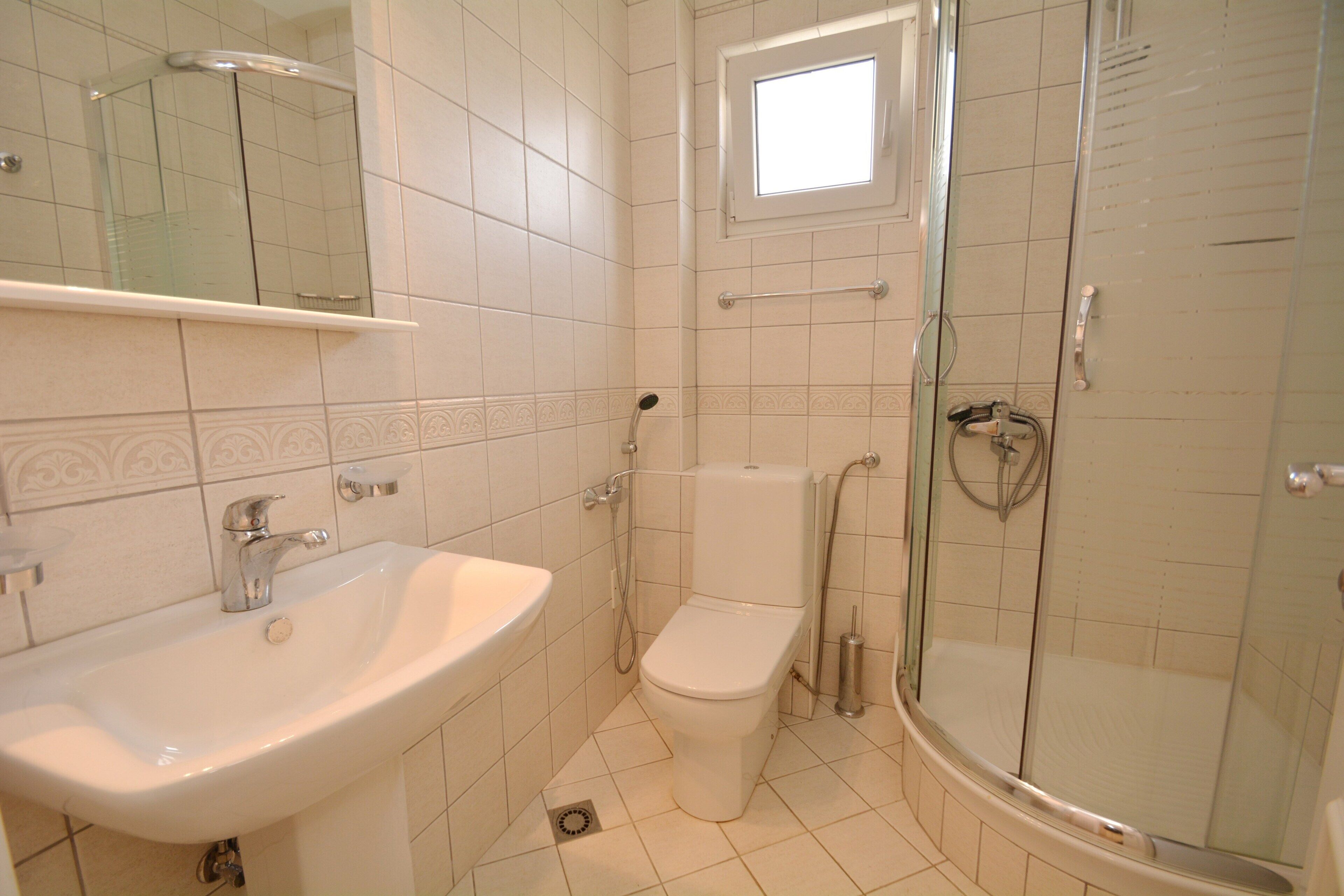 A bathroom with a sink, toilet, and glass-enclosed shower.