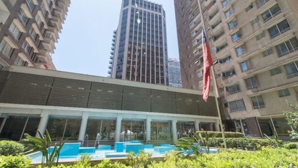 A modern building with a swimming pool and a flag. - VR Suite (Santiago)