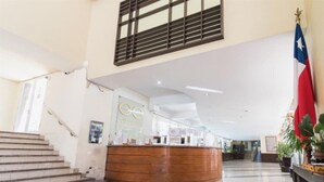 A reception area with a wooden counter, a staircase, and a flag. - VR Suite (Santiago)