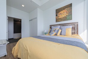 Relax in a serene bedroom with a large bed, a painting above, and a bedside table with a lamp.