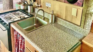 A kitchen with granite countertops, stainless steel appliances, and hanging pots.