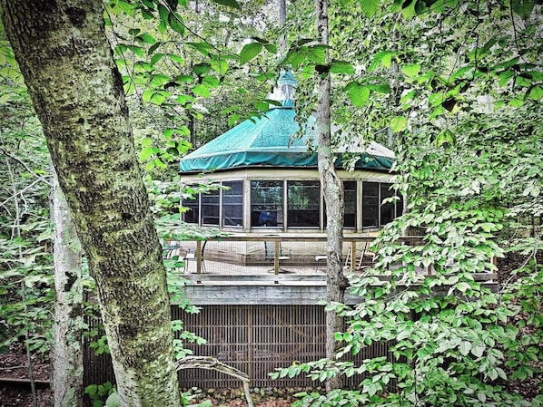 A gazebo with a green roof, surrounded by trees.