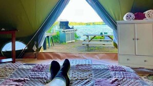 A tent with a bed, a table, and a view of a lake. - Glamping Lakefront Island Retreat w/ Kayak & Pet-Friendly (Monmouth)