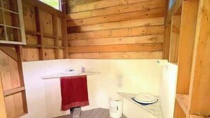 A wooden cabin with a small bathroom, a red towel, and a bucket. - Glamping Lakefront Island Retreat w/ Kayak & Pet-Friendly (Monmouth)