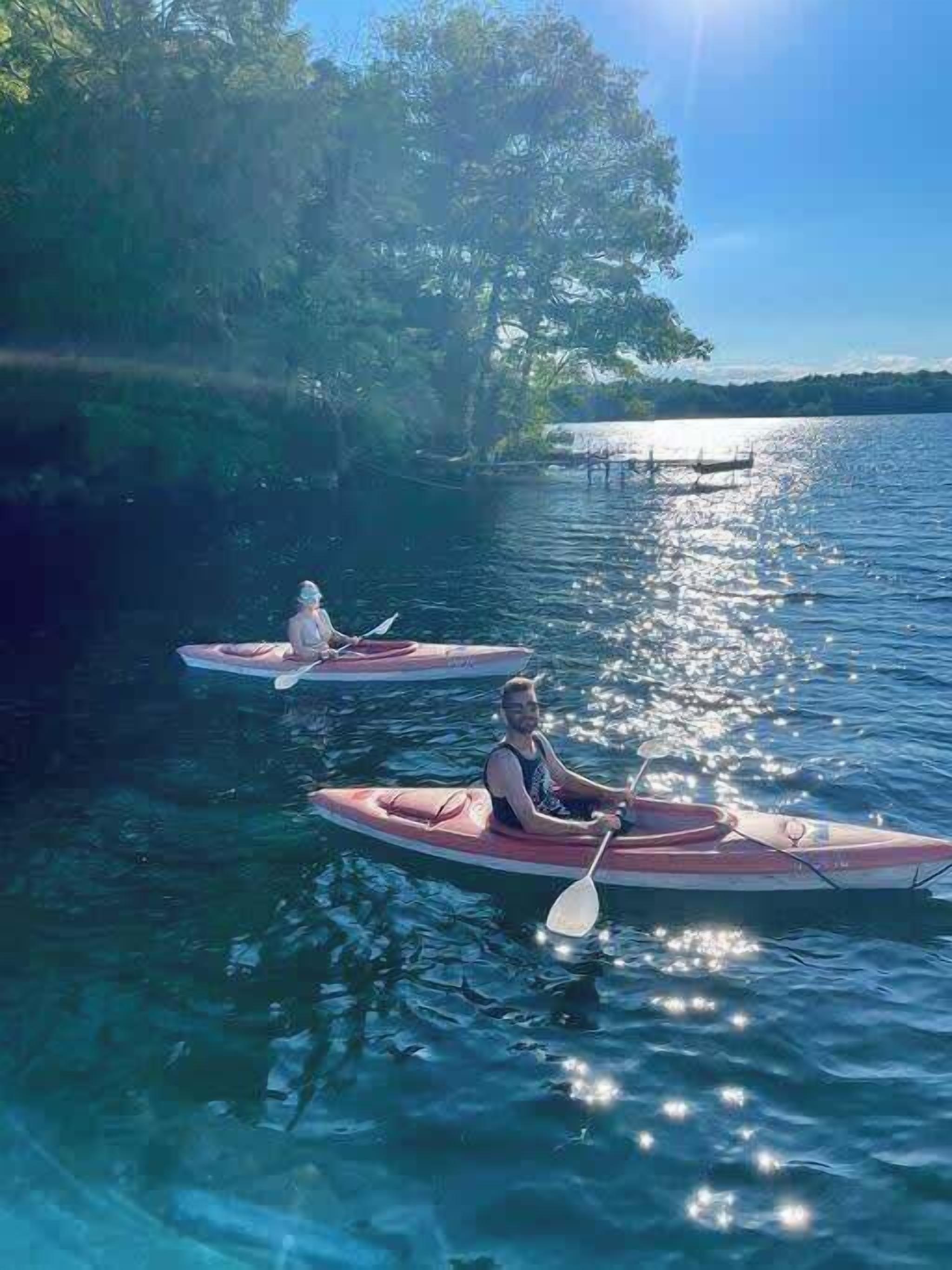 Two kayaks on a calm lake with trees and a dock in the background.