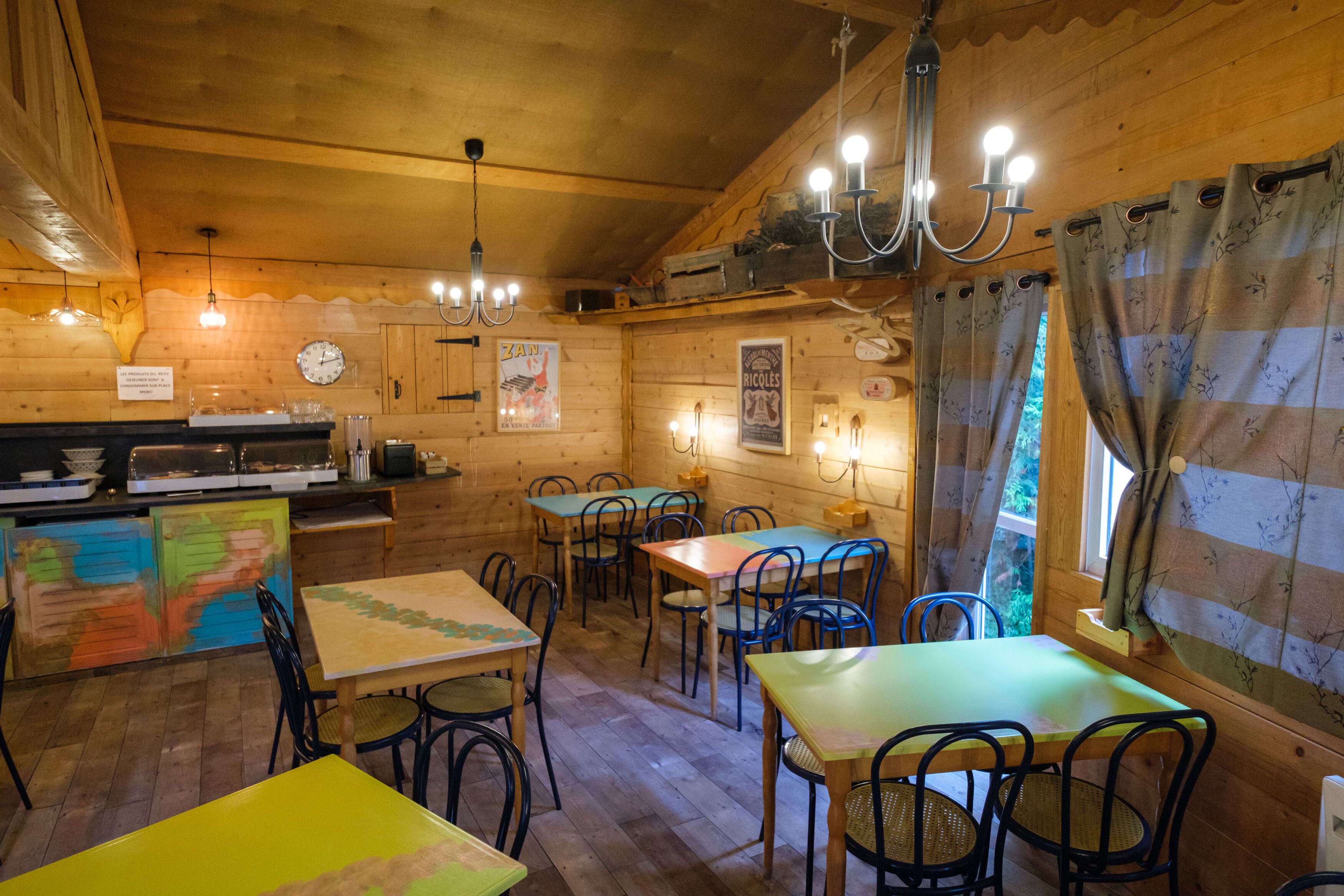 Un comedor de estilo cabaña de madera con mesas y sillas, un reloj y una araña.