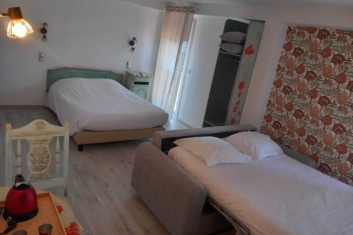 Ein Schlafzimmer mit zwei Betten, einem Nachttisch, einem Spiegel und einem Fenster mit Vorhängen.