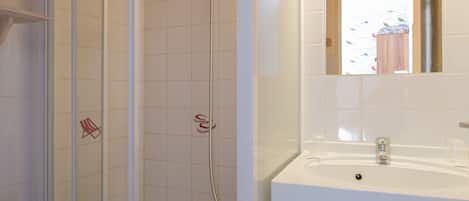 A bathroom with a glass-enclosed shower, a white sink, and a wooden vanity.