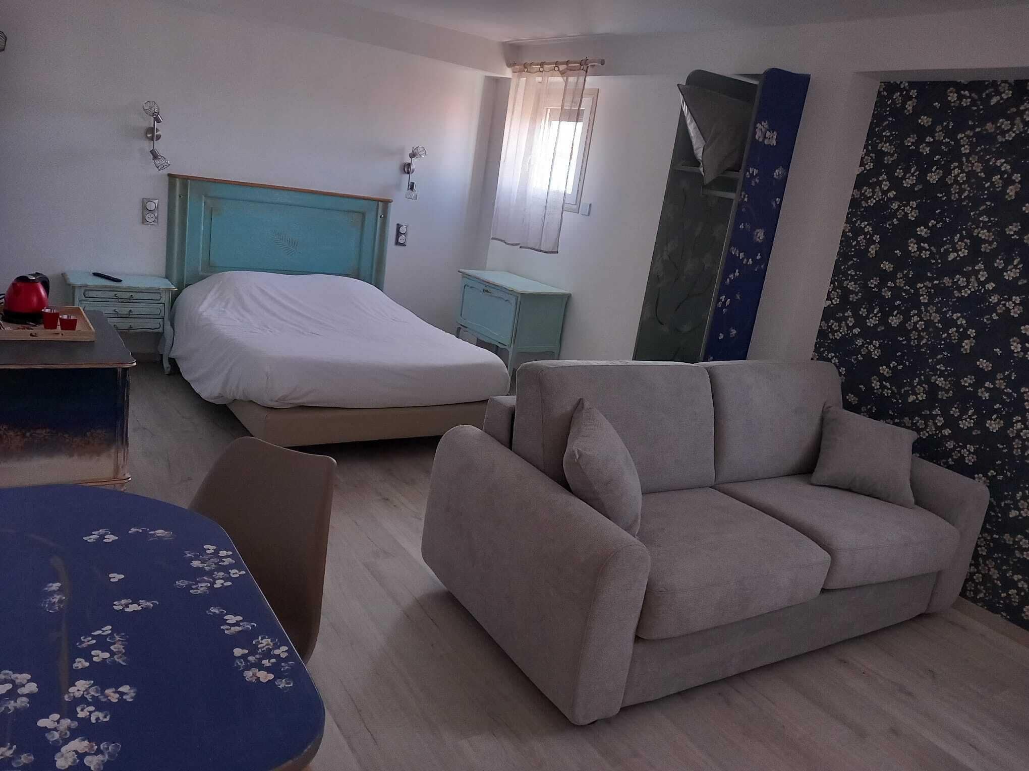 Une pièce comprenant un lit, un canapé, une table et un miroir.