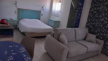 Une pièce comprenant un lit, un canapé, une table et un miroir.