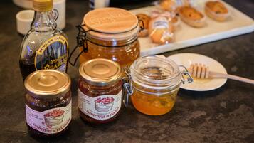 A table with various food items including jars of honey and jam, a honey dipper, and pastries.