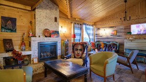 Een gezellige kamer met een open haard, houten wanden, een televisie en comfortabele zithoek.