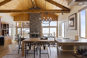 Experience the perfect blend of natural materials and modern design in this inviting space, featuring a stone pillar, wooden dining table, and comfortable seating area.