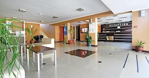 A reception area with a reception desk, a staircase, and potted plants. - Hotel Pliska (Nessebar)