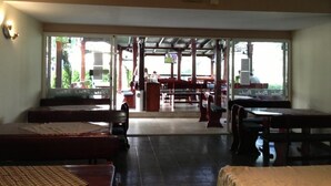 An indoor seating area with tables and benches, a counter, and a view through a glass door to the outside. - Hotel Pliska (Nessebar)