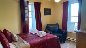 A hotel room with a bed, a chair, and a desk.