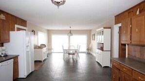 Eine geräumige Küche mit Holzausstattung, einem weißen Kühlschrank und einem Essbereich mit Tisch und Stühlen.