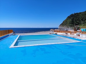 A pool area with a view of the ocean, a wooden deck, and a lifeguard chair. - Casa do Sanguinho - Faial da Terra. Nature right outside your door, trails, and the ocean. (Faial da Terra)
