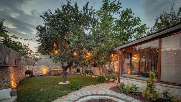A backyard with a stone fire pit, a tree, and a patio area with outdoor furniture.